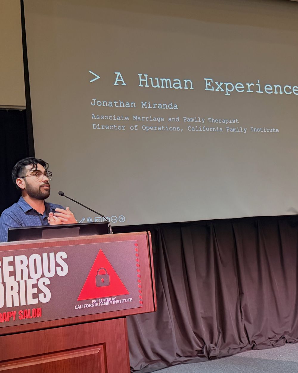 Presenter at the lectern under the title slide A Human Experience
