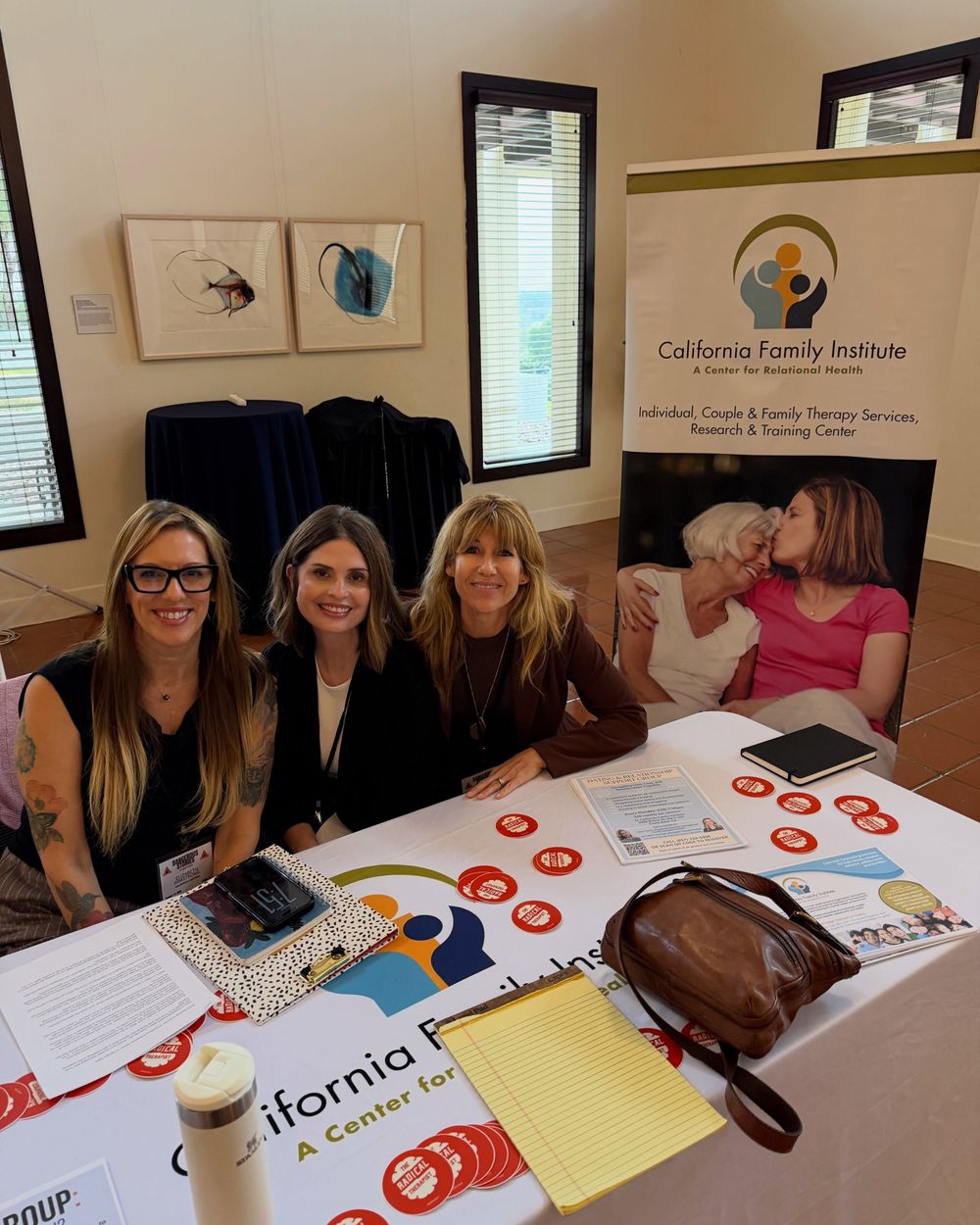 Three people smiling behind the California Family Institute information table